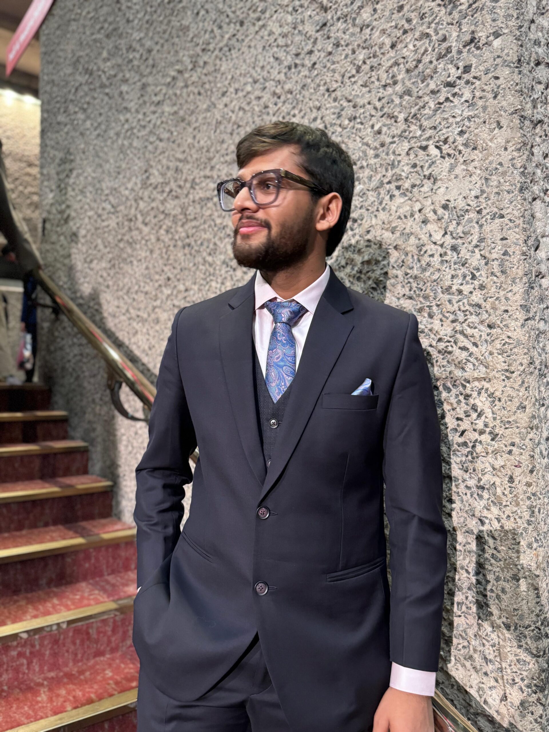 a man in a suit standing in front of a body of water